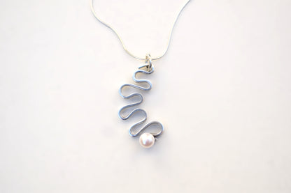 A silver wavy spiral pendant necklace with a single white pearl, shown on a thin silver chain against a plain white background.