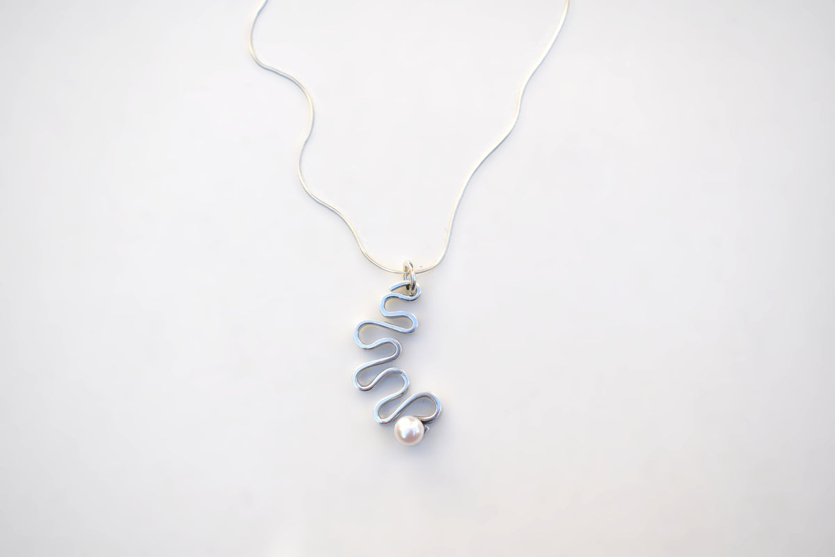 A delicate silver wire pendant necklace with a wavy, coiled design and a small white pearl accent, displayed on a clean white background.