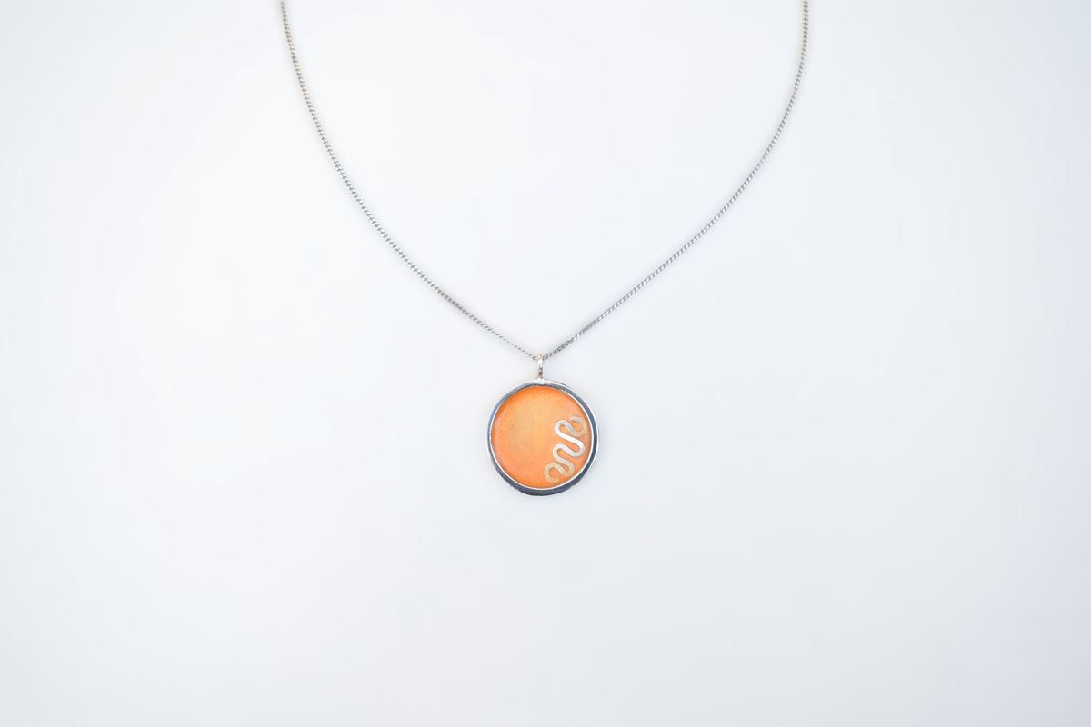 A silver chain necklace with a circular pendant featuring a textured orange background and the white cursive text 'Sue' inside, displayed against a plain white background.