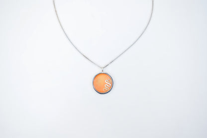 A silver chain necklace with a circular pendant featuring a textured orange background and the white cursive text 'Sue' inside, displayed against a plain white background.